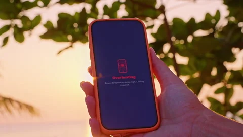 Smartphone Screen Showing Overheating Warning Message in Hand at Sunset with Tro Stock Footage 332304578