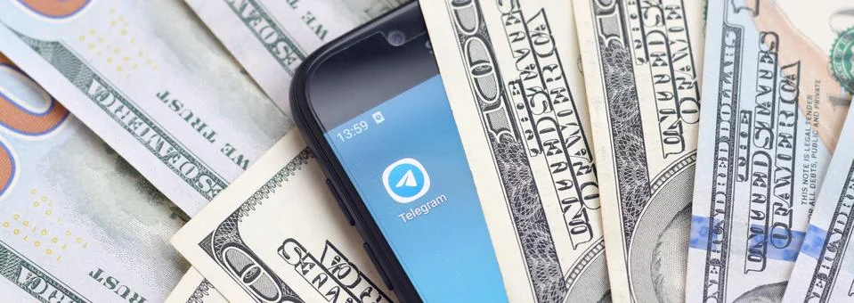 Smartphone screen with Telegram app and lot of hundred dollar bills. Business Foto stock