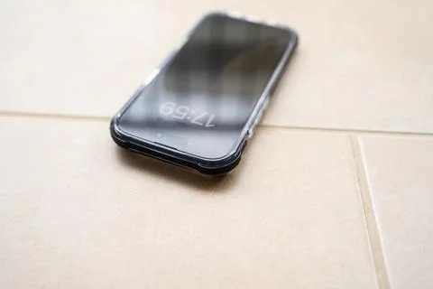 Smartphone in shockproof silicone case on tiled floor after falling. Stock Photos