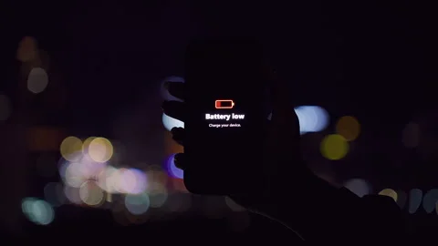 Smartphone Showing Battery Low Warning Held Against Colorful Night City Bokeh in Video stock 323466754