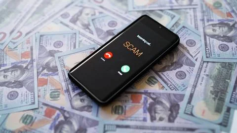 Smartphone showing scam call on screen lying on dollars. Stock Photos
