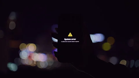 Smartphone Showing System Error Alert with Yellow Triangle Held Against Night Ci Stock Footage 323466450