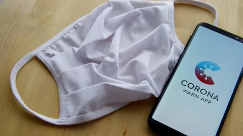 Smartphone with splash screen of German Corona Warn App with white face mask Stock Footage 131922011