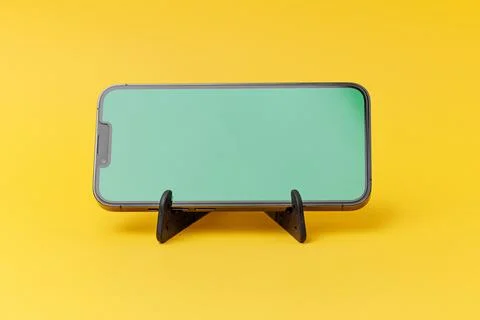 Smartphone on tiny stand with a greenscreen to replace content Stock Photos
