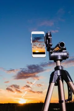 Smartphone on tripod capturing image of sundown in vertical mode Stock Photos