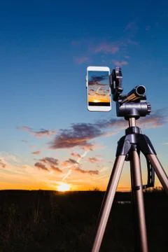 Smartphone on tripod capturing image of sundown in vertical mode Stock Photos