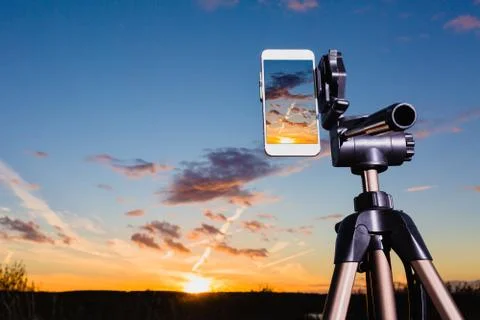 Smartphone on tripod capturing image of sundown in vertical mode Stock Photos