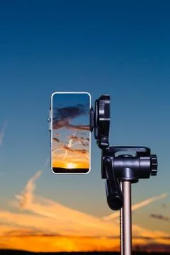 Smartphone on tripod capturing image of sundown in vertical mode Stock Photos