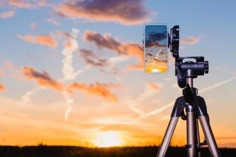 Smartphone on tripod capturing image of sundown in vertical mode Foto stock