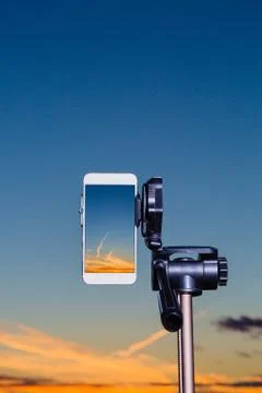 Smartphone on tripod capturing image of sundown in vertical mode 写真素材