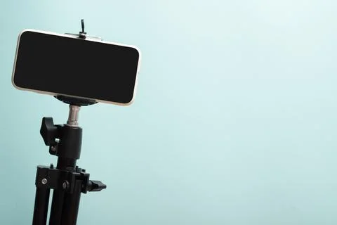 Smartphone on a tripod on a light blue background. The desktop of a modern bl Stock Photos