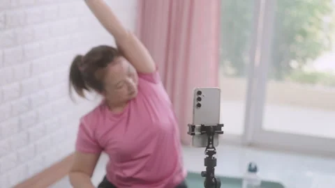 Smartphone on tripod streaming yoga tutorial at home Stock Footage 310037770