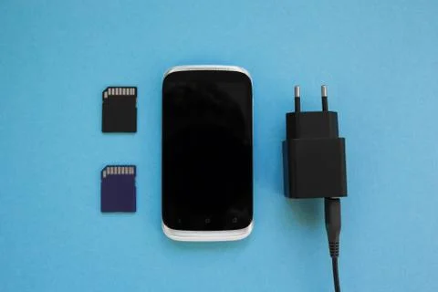 The smartphone, a two memory card and charger on a blue background. Stock Photos