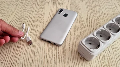 Smartphone with USB Cable and Power Strip on Wooden Surface Stock Footage 339846970