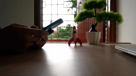 Smartphone Use at Desk with Toy Rocket and Plant Stock Footage 320725630