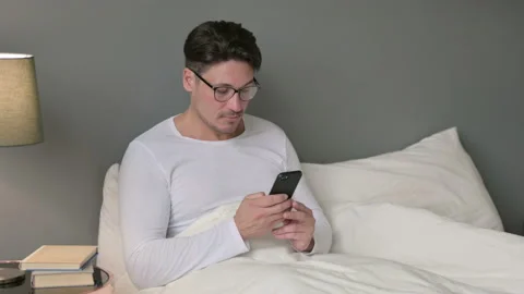Smartphone use by Serious Middle Aged Man in Bed 스톡 동영상 142367510