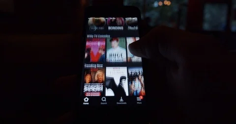 Smartphone user looking for suitable movie or tv show on Netflix streaming app Stock Footage 107278670