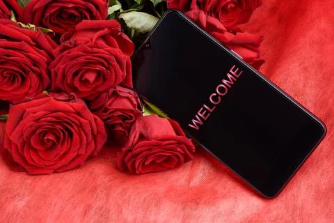 Smartphone with Welcome Text on Screen Lying on Red Roses Bouquet Stock Photos