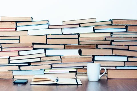 Smartphone, white cup, stack of books, notebook and pencils on wooden table,  Stock Photos