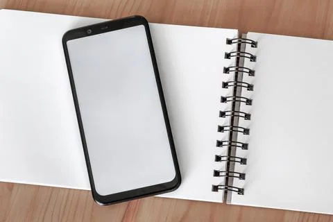 Smartphone with white screen on open notebook for overlay mock-up Stock Photos