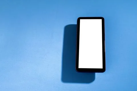 Smartphone with white screen on top of blue table. Cell phone concept. White  Stock Photos