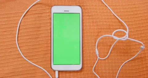 Smartphone with wired headphones connected is lying on blanket, with an empty Stock Footage 161286610