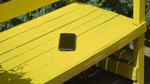 Smartphone on a yellow bench. lost smart phone concept Stock Footage 325358789