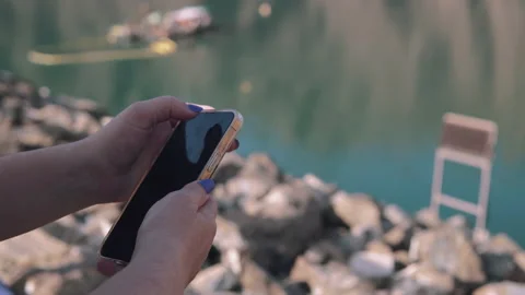 Smartphone.Woman standing down the lake and stones and setting up his smartphone Stock Footage 205032402