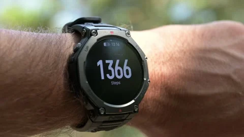 Smartwatch displaying daily step count tracking on a man's wrist outdoors Stock Footage 346073289