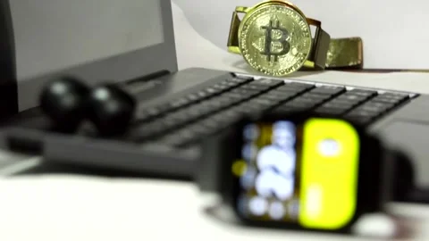 Smartwatch lying in front of a computer, Bitcoin coins on a white background Stock Footage 342257112