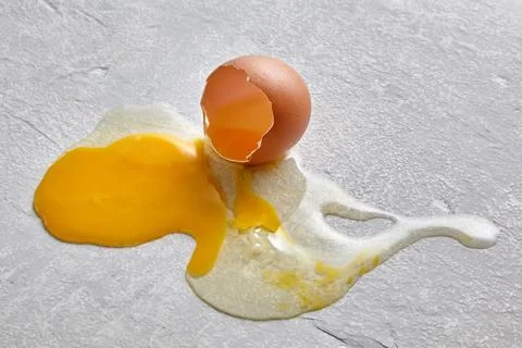The smashed chicken egg splattered across the concrete floor Stock Photos