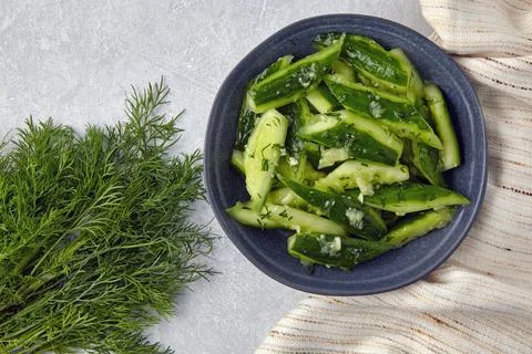 Smashed lightly salted broken cucumbers in a ceramic bowl surrounded by dill  Foto stock