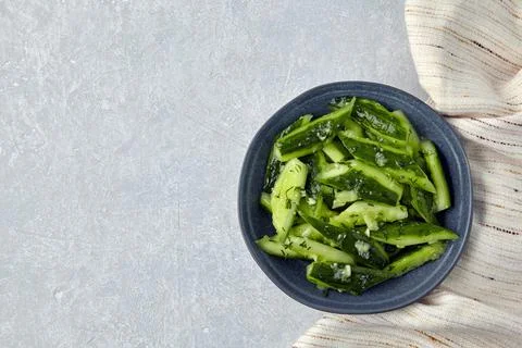 Smashed lightly salted broken cucumbers in a ceramic bowl surrounded by dill and Foto stock
