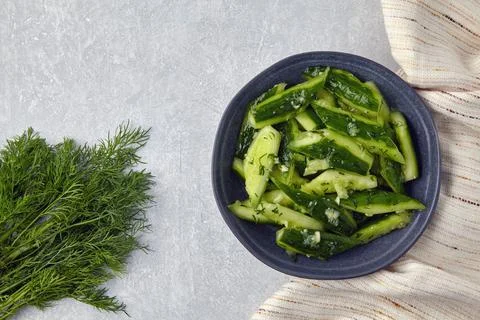 Smashed lightly salted broken cucumbers in a ceramic bowl surrounded by dill  Stock Photos