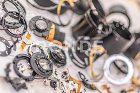 A smashed up telephoto zoom lens in parts on a table Stock Photos