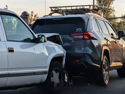 A smashed white SUV sits damaged after rear-ending another vehicle at sunset Stock Photos