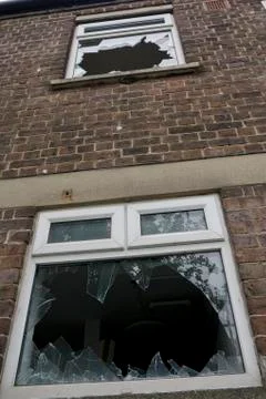 Smashed windows on front of home _ damage to residential property Stock Photos