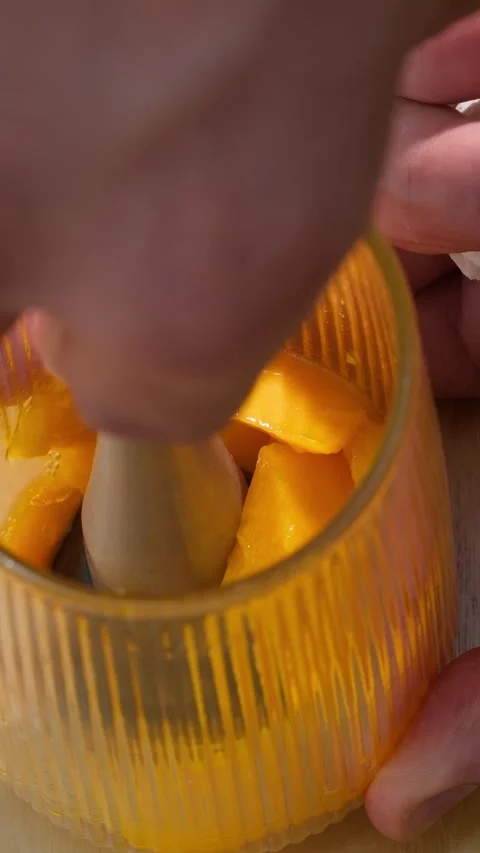 Smashing fresh mango in a glass to prepare refreshing summer drink. Vertical Stock Footage 314458907