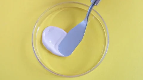 Smear of beige base for makeup or concealer in Petri dishes on yellow background Stock Footage 276533054