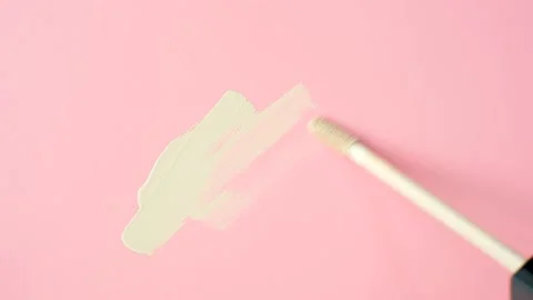 Smear with a brush of beige foundation or concealer on a pink background close Video stock 237591699