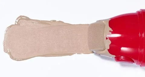 A smear of foundation, beige liquid texture, red applicator with a sponge. Stock Photos