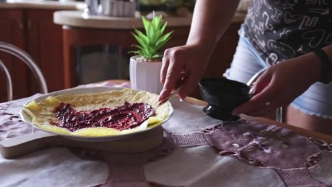 Smearing cherry jam on a pancake rolling it and leaving it on a plate in dini Stock Footage 150202822