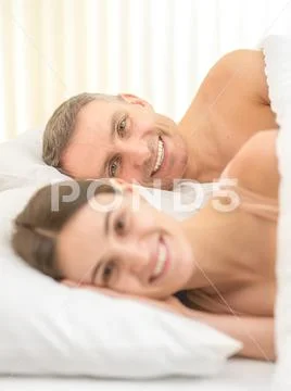 The smile couple lay on the bed Stock Photos