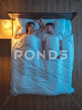The smile couple lie on the bed. evening night time. view from above Stock Photos