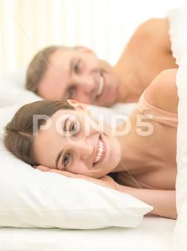 The smile couple lie on the bed Stock Photos