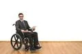 The smile disabled in a wheelchair holding papers on the white wall backgroun Photo