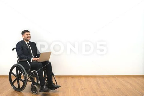The smile disabled working with a laptop on the white wall background Stock Photos