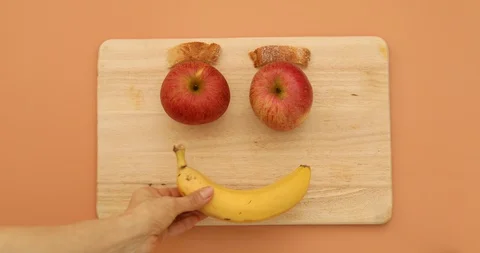 Smile face shape with apples and banana and bread on wooden cutting board Stock Footage 128685682