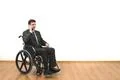 The smile man in the wheelchair phones on the white wall background Photo