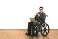 The smile man in a wheelchair sitting with a laptop on a white wall backgroun Photo